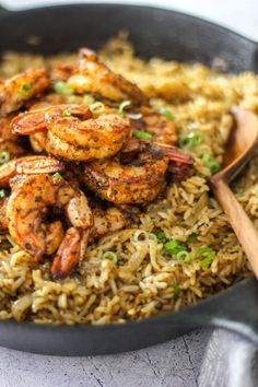 shrimp and rice in a skillet with a wooden spoon on the side, ready to be eaten