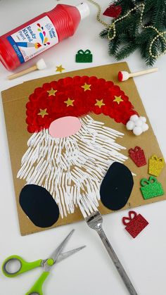 paper plate santa craft with scissors, glue and other crafts on the table next to it