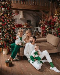 a family sitting on the floor in front of christmas trees