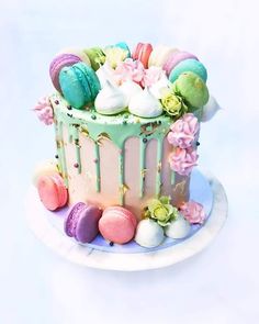 a colorful cake with macaroons and flowers on it sitting on a white plate