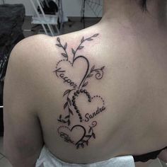 the back of a woman's shoulder with a heart and name tattoo on it