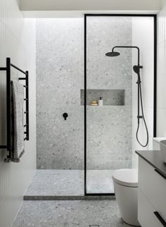 a bathroom with a walk in shower next to a white toilet and black accents on the walls