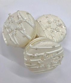 three white decorated cookies sitting next to each other on top of a table with silver stars