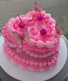 a cake with pink frosting and butterfly decorations on it's top, sitting on a plate