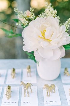 a vase filled with white flowers sitting on top of a table covered in tiny figurines