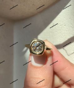 a person holding a ring with a diamond in it's middle and an inscription on the side