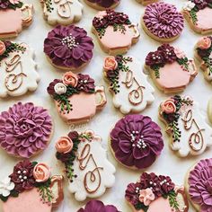 some decorated cookies are on a table with pink and purple flowers in vases,