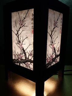 a lamp that is lit up with some flowers on the top and branches in the bottom