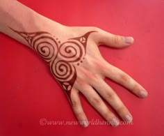 a person's hand with a henna tattoo on it, resting on a red surface