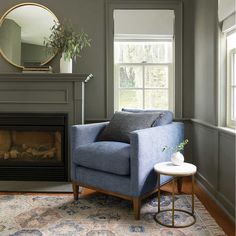 a living room with gray walls and a blue chair in front of a fire place