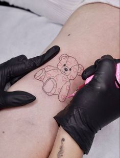 a person with black gloves on their legs has a teddy bear drawn on her thigh