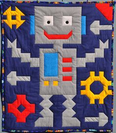 a quilted wall hanging with an image of a robot on it's side