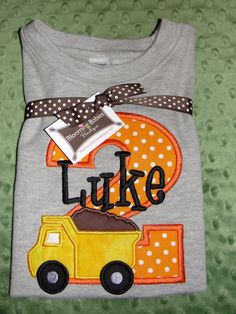 a gray shirt with a yellow dump truck and polka dot ribbon on the front that says luke