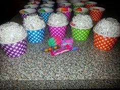 there are many cupcakes and candy in the cups on the counter top, all decorated with polka dots