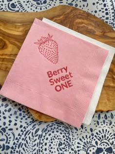 a pink napkin that says berry sweet one on it with a strawberry printed on the front