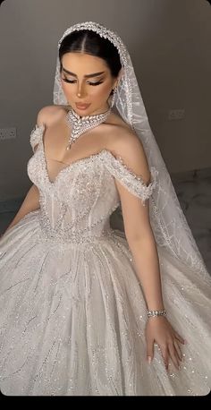 a woman in a wedding dress is wearing a tiara and holding her hand on her shoulder