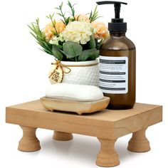 a wooden table topped with a vase filled with flowers and a soap dispenser