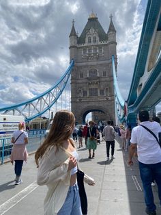 people are walking on the sidewalk in front of tower bridge