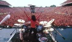 a person on stage with their arms in the air and hands raised above them as they play drums