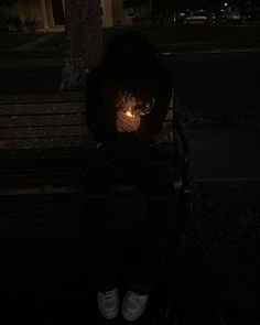 a person sitting on a bench at night with their head illuminated by a light bulb