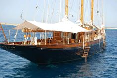 an old sailboat in the middle of the ocean with a canopy on it's side