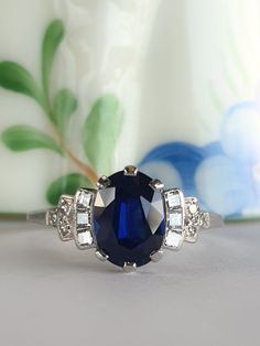 a blue and white diamond ring sitting on top of a table