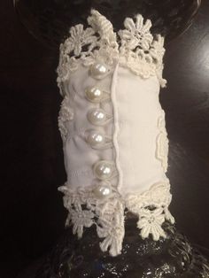 a close up of a vase with pearls on the bottom and lace trimming around it