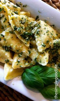 a white plate topped with ravioli and spinach covered in cheese, parsley