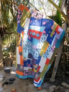 a colorful quilt is hanging on a tree