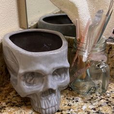 there is a skull cup and toothbrush holder on the counter