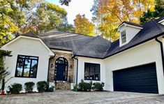 a white house with black shutters and two large garage doors on the front of it