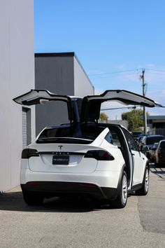 an electric car with its doors open parked in a parking lot next to a building