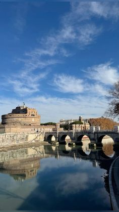 a bridge over a body of water with a castle in the background on a sunny day