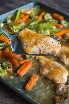 a spoon with some food on it and broccoli, carrots, and chicken