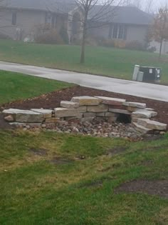 a fire pit sitting in the middle of a field next to a road and trees