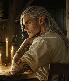 a man with white hair and tattoos sitting at a table in front of some candles