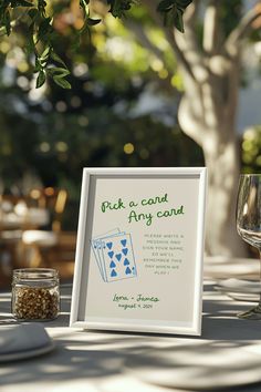 a table with a sign and wine glass on it that says pick a card any card