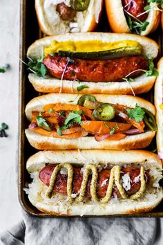 several hot dogs with toppings in a tray