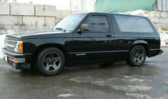 a black truck is parked in front of a building and some snow on the ground