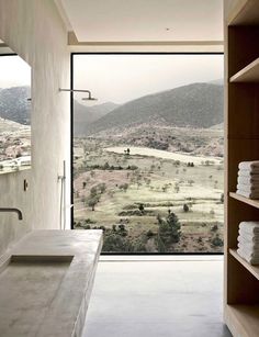 a bathroom with a large open window overlooking the hills and valleys in front of it