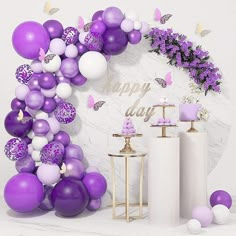 purple and white balloons are hanging on the wall next to two vases with flowers