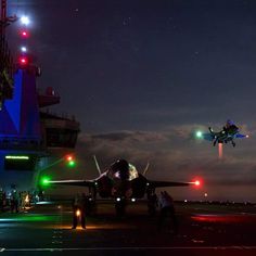 an airplane that is sitting on the runway at night with other planes in the background