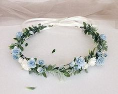 a white and blue flower headband with greenery on the side, sitting on a table