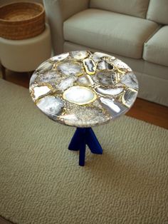 a small table sitting on top of a blue tripod in front of a couch