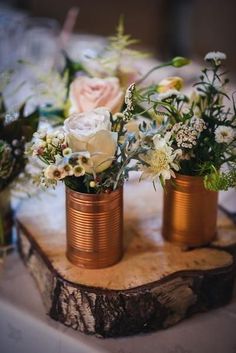 three vases filled with flowers sitting on top of a wooden slab covered in wood