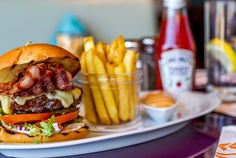 a bacon cheeseburger with fries and ketchup on the side at a restaurant