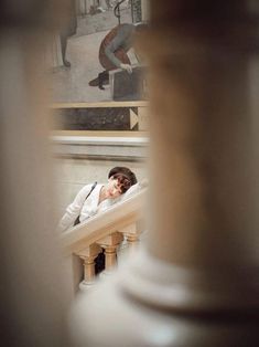 a woman is laying down on the stairs in front of a building with a painting behind her