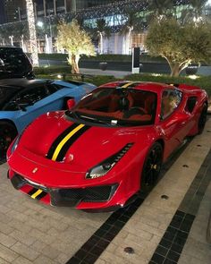 three different colored sports cars parked next to each other in front of a building at night