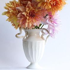 a white vase filled with lots of colorful flowers