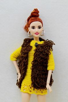 a doll is wearing a yellow dress and brown vest with her hands on her hips